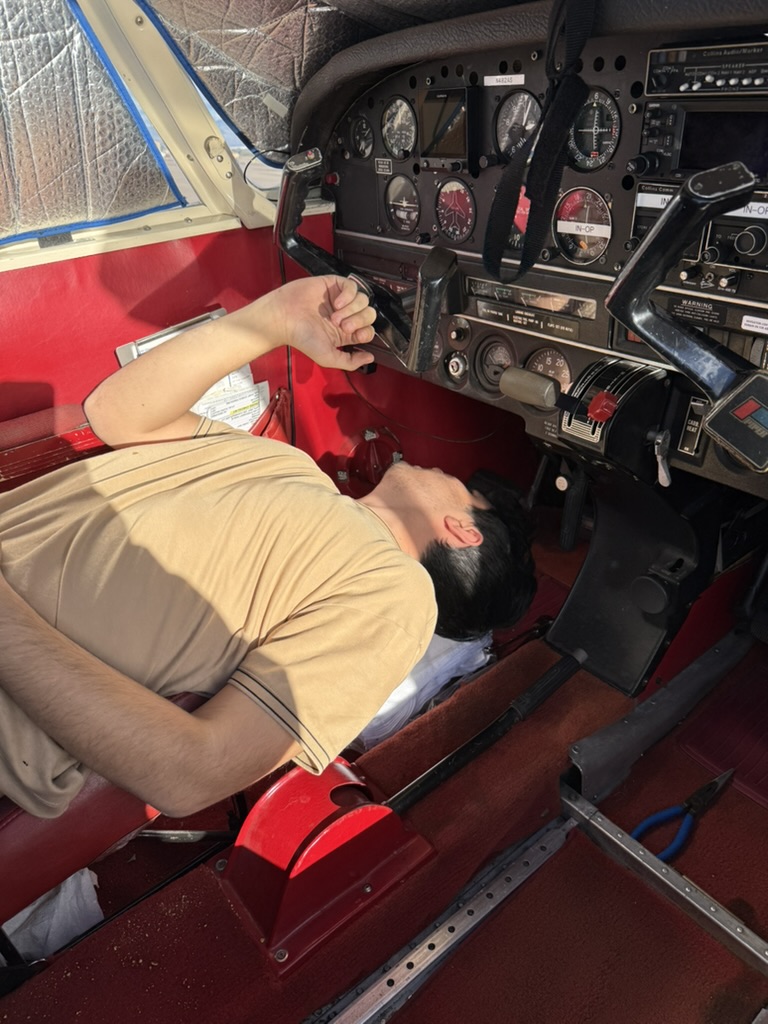 Mechanic working upside down under a Piper instrument panel